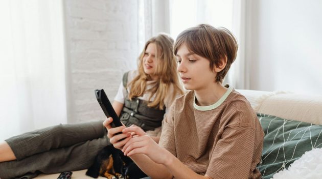 2 enfants dans un canapé qui choisissent un programme TV